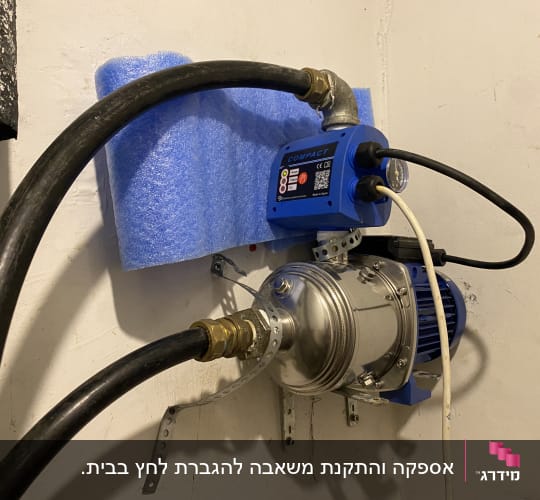 משאבה כחולה מותקנת על קיר עם צינורות מחוברים